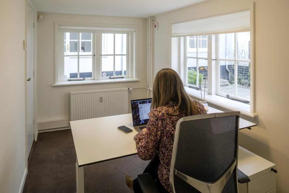 Vrouw werkt op een laptop in een lichte kantoorruimte aan de Keizersgracht 97.