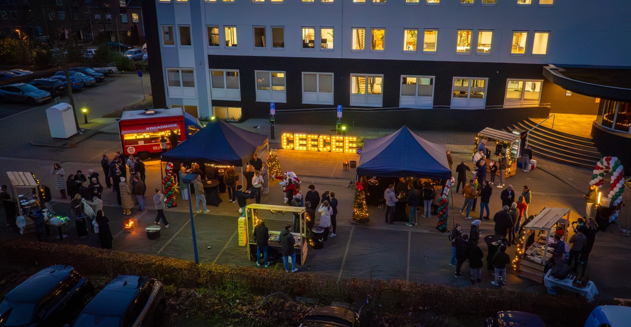 Overzicht van de gezellige kerstmarkt bij CeeCee, met kraampjes, lichtletters en bezoekers in wintersfeer.