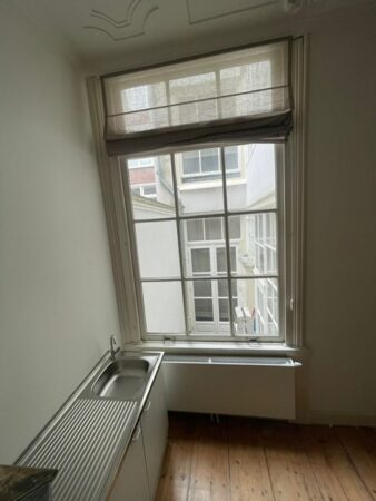 Kleine kitchenette met spoelbak en groot raam met uitzicht op binnenplaats aan Kloveniersburgwal 56.