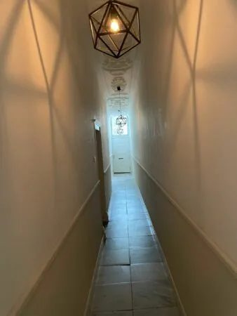Smal verlicht gangpad met versierde plafondlijsten en geometrische hanglampen in Kloveniersburgwal 56.