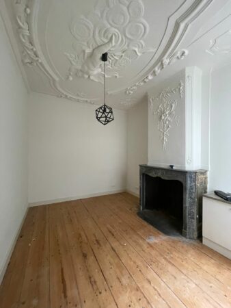 Lege kamer in Kloveniersburgwal 56 met houten vloer, sierplafond en marmeren open haard.