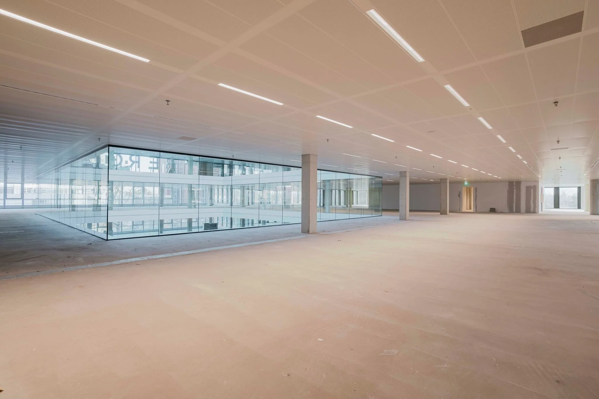 Leeg kantoorpand aan het Koning Wilhelminaplein 4 met een glazen vergaderruimte en modern systeemplafond.