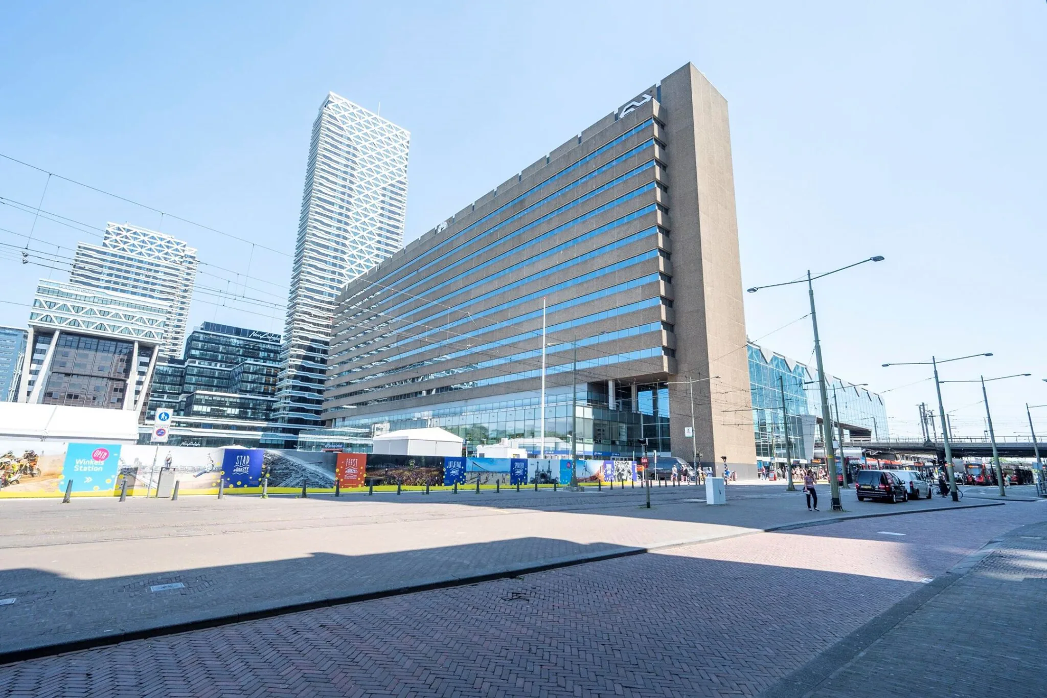 Modern kantoorgebouw aan het Koningin Julianaplein in Den Haag met op de achtergrond hoge torens en het treinstation.