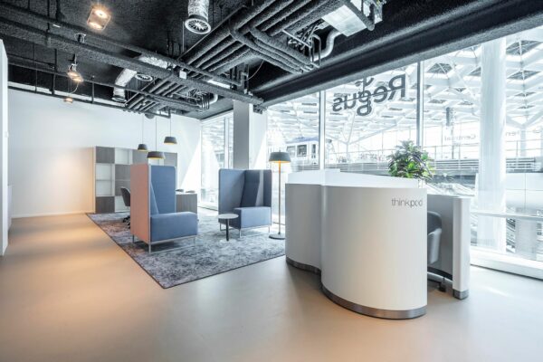 Moderne, lichte kantoorruimte aan het Koningin Julianaplein met flexwerkplekken, vergaderstoelen en een thinkpod bij grote ramen.