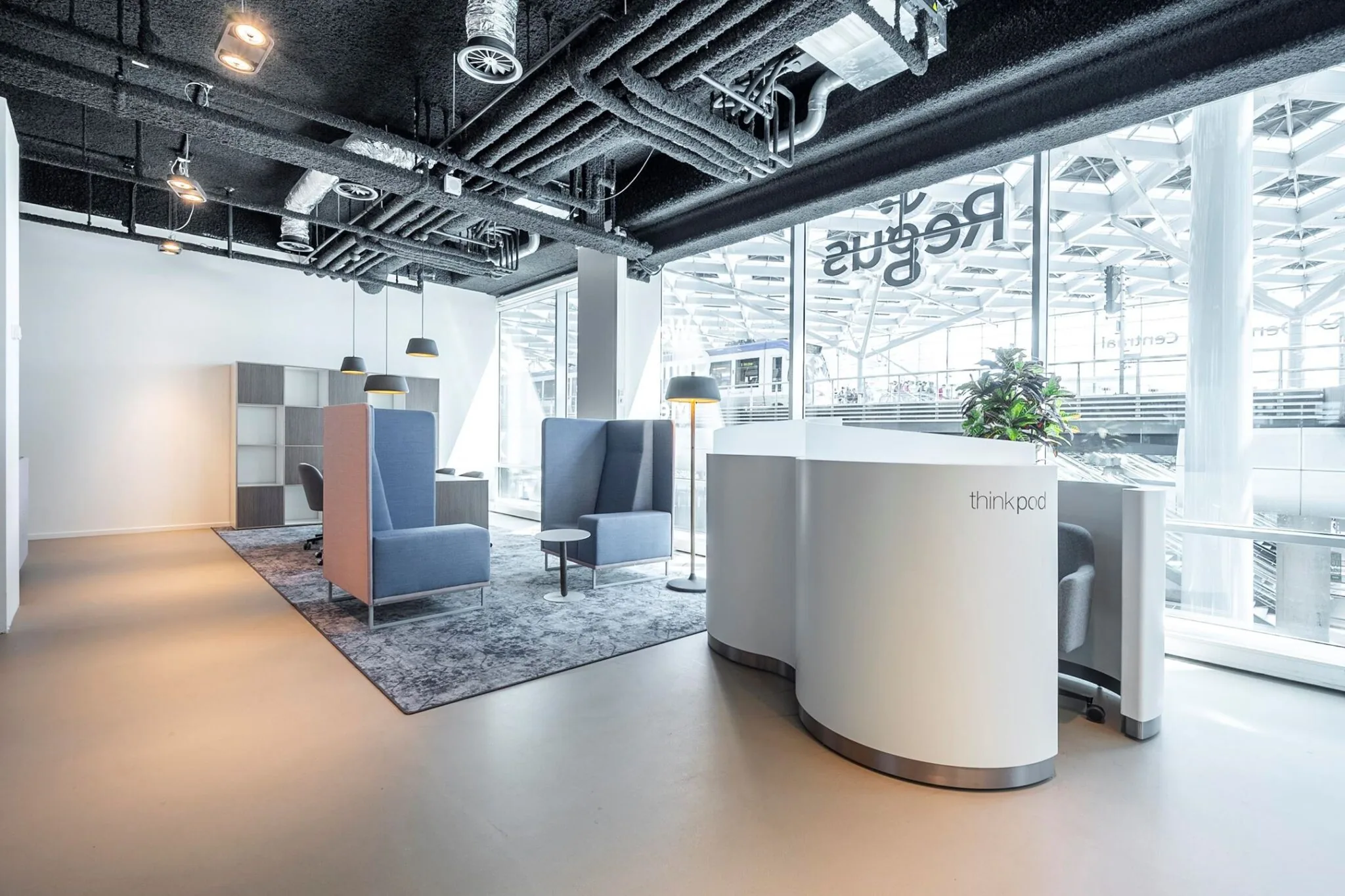 Moderne, lichte kantoorruimte aan het Koningin Julianaplein met flexwerkplekken, vergaderstoelen en een thinkpod bij grote ramen.