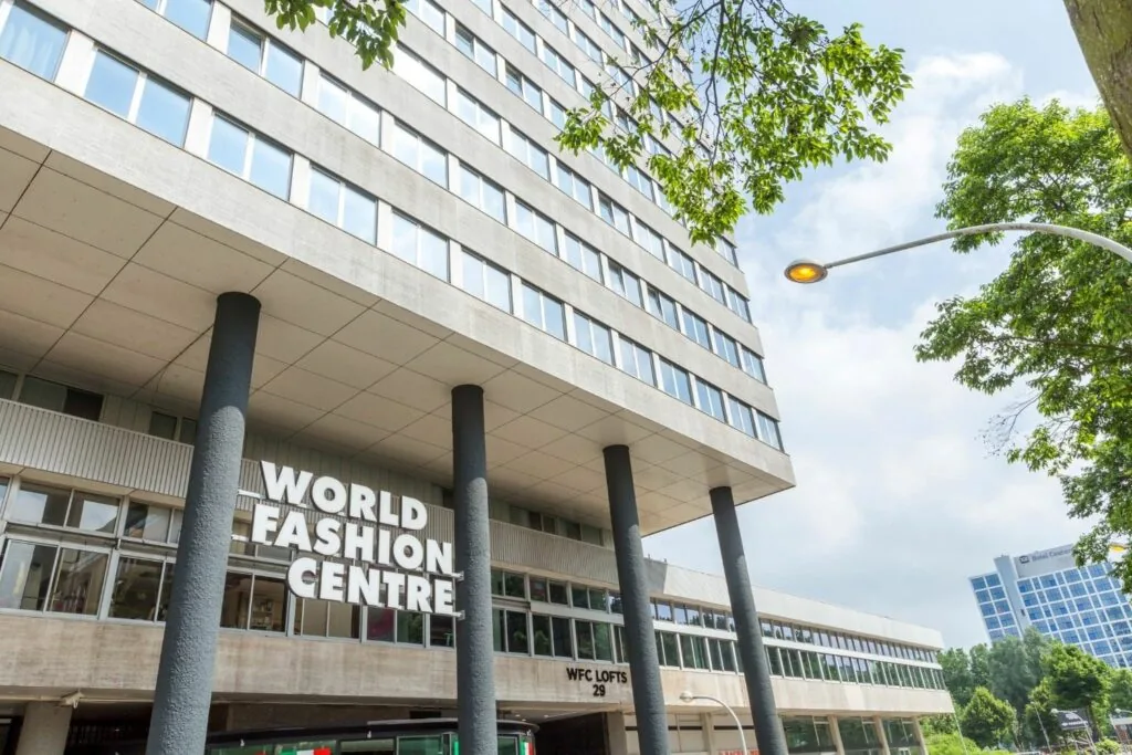 Vooraanzicht van het World Fashion Centre aan het Koningin Wilhelminaplein in Amsterdam, met opvallende gevel en steunpilaren.