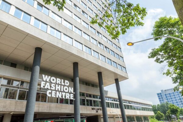 Vooraanzicht van het World Fashion Centre aan het Koningin Wilhelminaplein in Amsterdam, met opvallende gevel en steunpilaren.