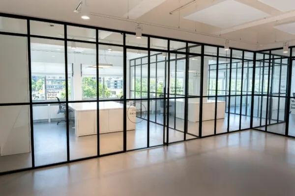 Moderne kantoorruimte met glazen wanden en uitzicht op het Koningin Wilhelminaplein in Amsterdam.