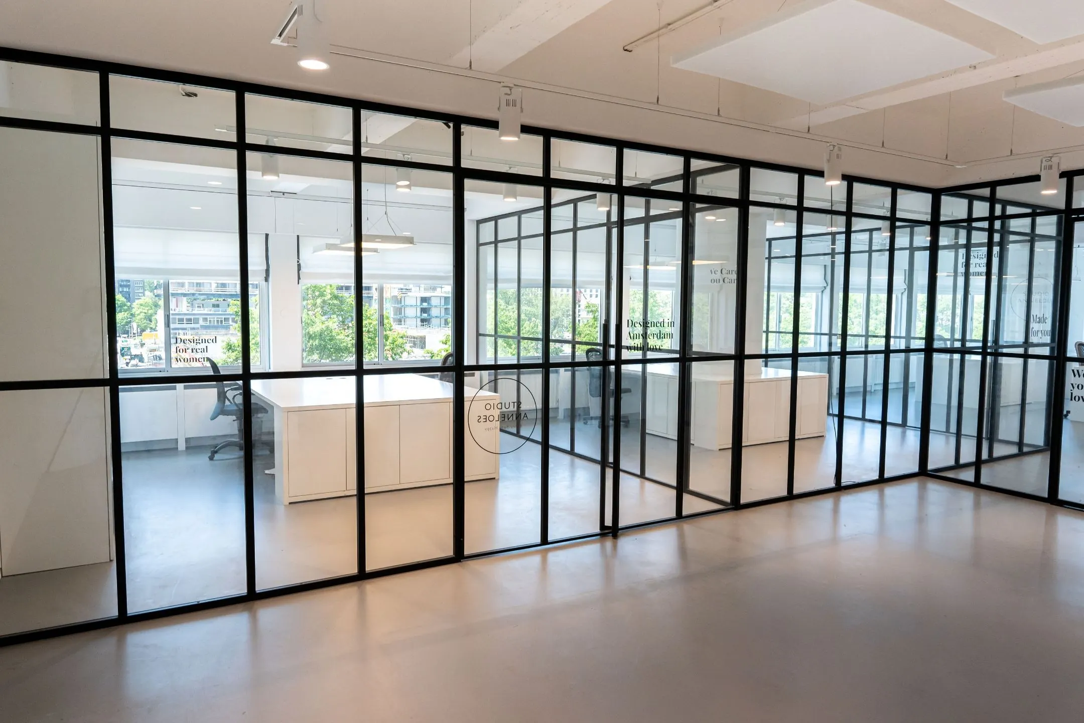 Moderne kantoorruimte met glazen wanden en uitzicht op het Koningin Wilhelminaplein in Amsterdam.