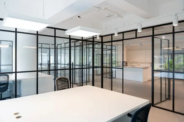 Modern kantoorinterieur op Koningin Wilhelminaplein 13_6 met glazen wanden, witte bureaus en een open keukenruimte.