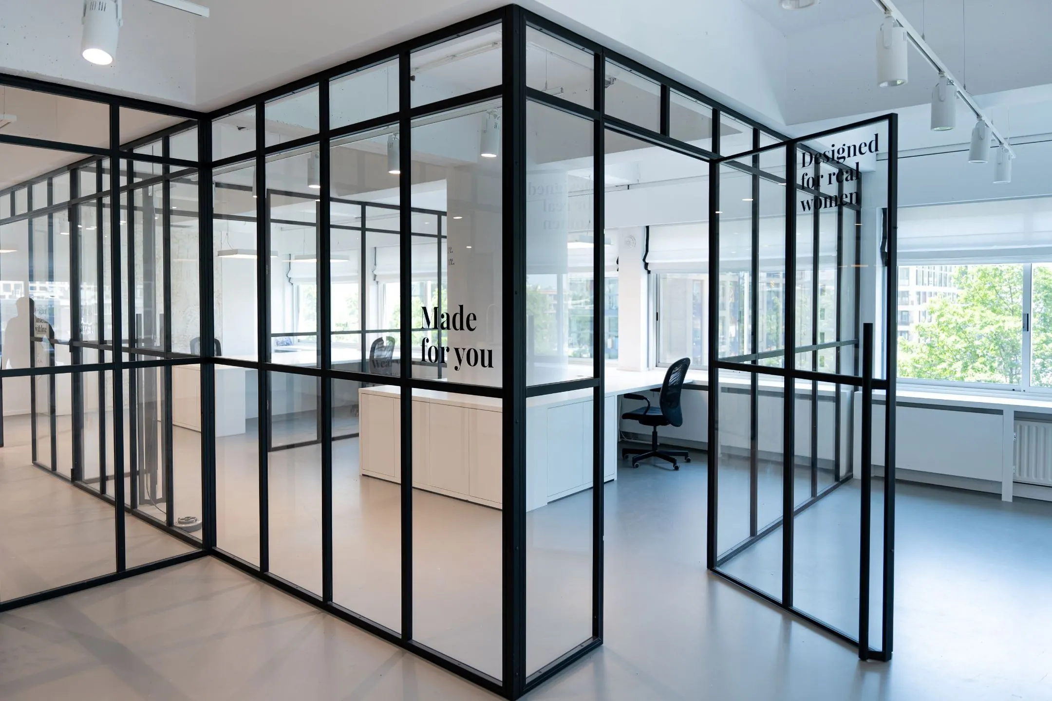 Moderne kantoorruimte aan het Koningin Wilhelminaplein 13 met glazen wanden, licht interieur en de teksten “Made for you” en “Designed for real women” op de ramen.