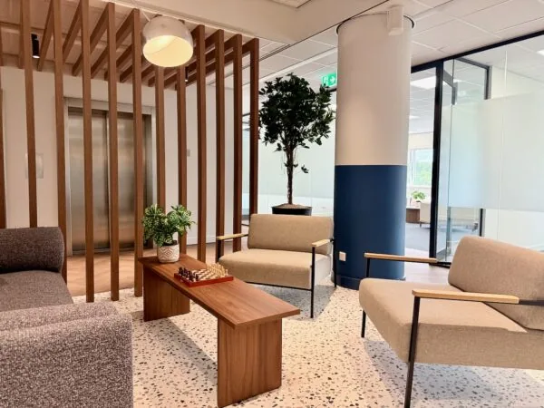 Moderne lounge in Kronenburg Offices met stijlvolle zitmeubels, houten accenten en een schaakbord op de salontafel.