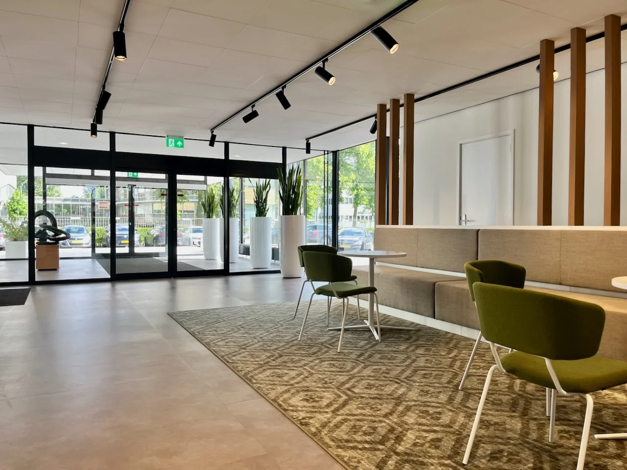 Moderne entreehal van Kronenburg Offices Ingang 1 met zitgelegenheid, grote ramen en planten in witte potten.