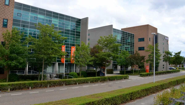 Modern kantoorgebouw aan de Laan van Vredenoord 33 met glazen gevel, omringd door bomen en een rustige straat.