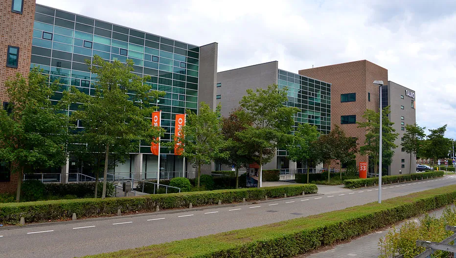 Modern kantoorgebouw aan de Laan van Vredenoord 33 met glazen gevel, omringd door bomen en een rustige straat.