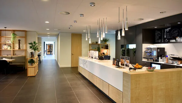 Moderne receptiebalie met koffiehoek in de entree van Laan van Vredenoord 33.