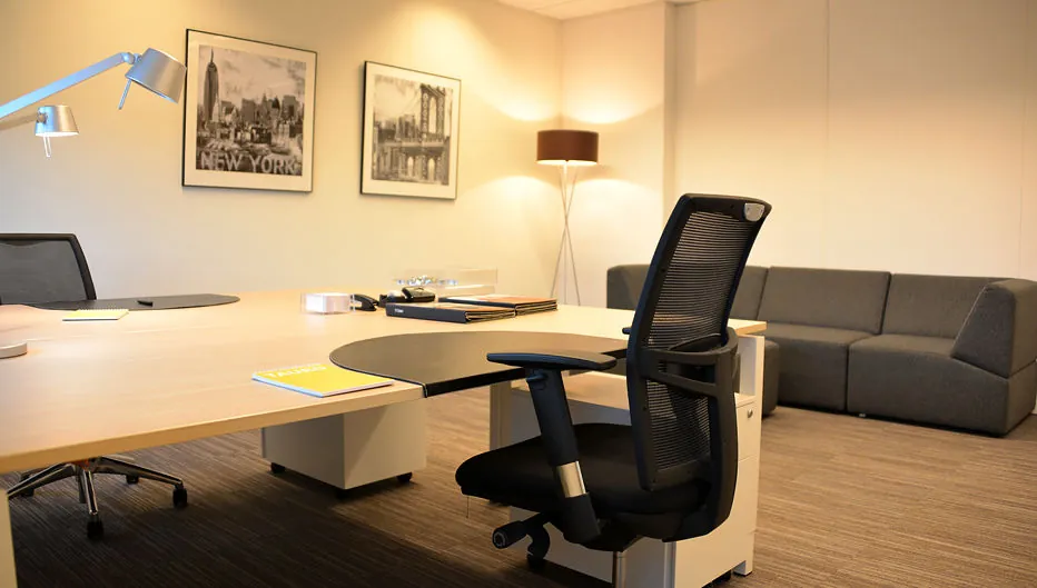 Modern ingericht kantoor aan de Laan van Vredenoord 33 met bureau, bureaustoel, bank en wanddecoratie.