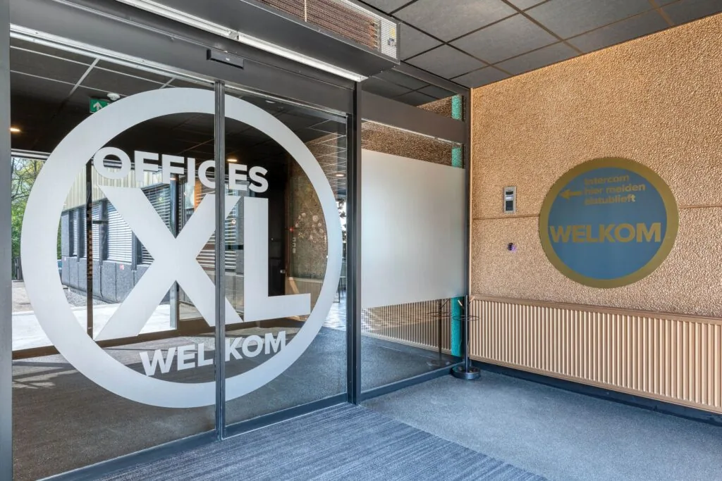 Ingang van het kantoorgebouw Offices XL aan de Laapvelderweg 15 met automatische schuifdeur en welkomstbord bij de intercom.