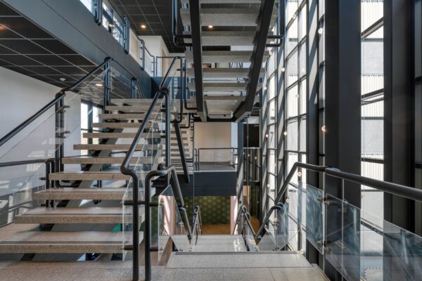 Moderne trapconstructie met glazen balustrades en betonnen treden in een licht atrium aan de Laapvelderweg 15.