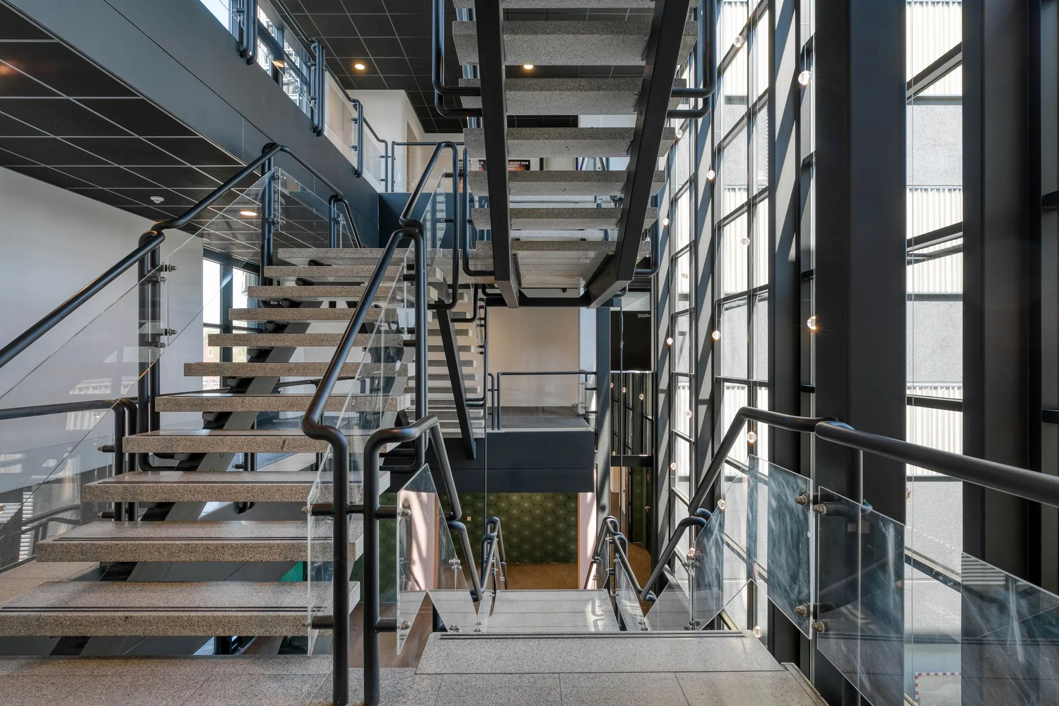 Moderne trapconstructie met glazen balustrades en betonnen treden in een licht atrium aan de Laapvelderweg 15.