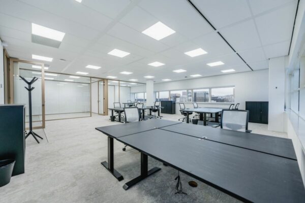 Moderne, ruime kantoorruimte aan de Laarderhoogtweg 7 met bureaus, bureaustoelen en glazen vergaderruimtes.