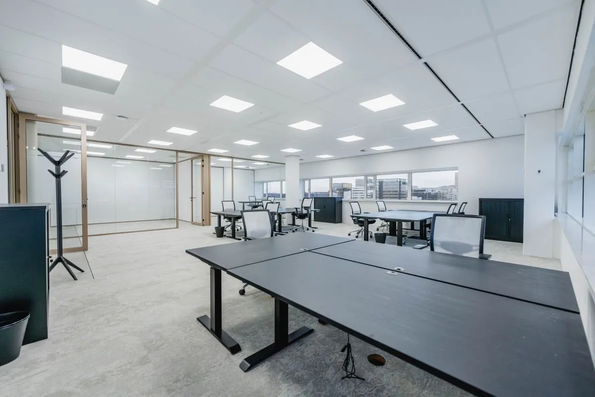 Moderne, ruime kantoorruimte aan de Laarderhoogtweg 7 met bureaus, bureaustoelen en glazen vergaderruimtes.