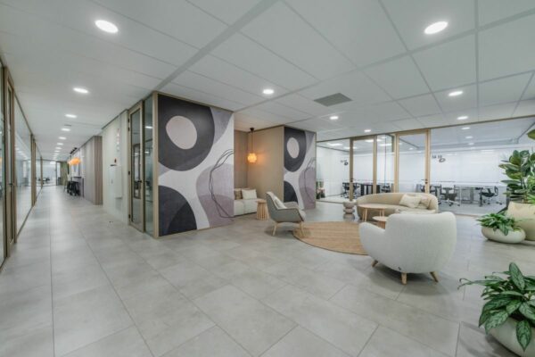 Moderne en stijlvol ingerichte kantoorruimte aan de Laarderhoogtweg 7 met zitgedeelte, kunst aan de muur en glazen vergaderruimtes.