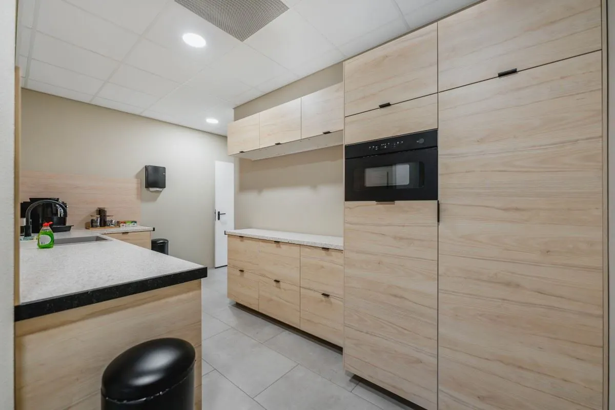 Moderne pantrykeuken aan de Laarderhoogtweg 7 met licht houten kasten, ingebouwde magnetron en koffiehoek.