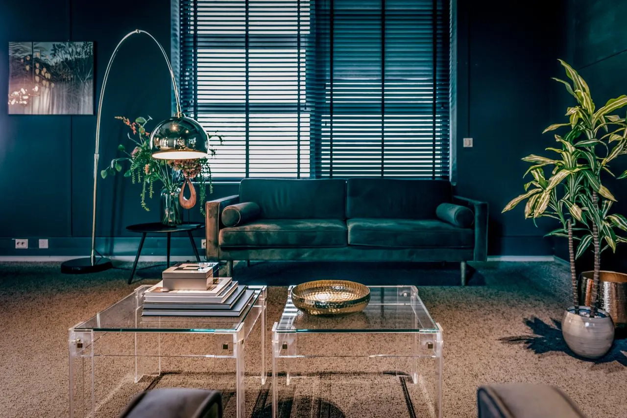 Stijlvolle woonkamer aan de Lange Amerikaweg 61 met een donkergroene bank, designverlichting en glazen salontafels.