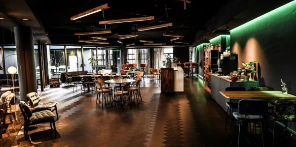 Moderne en sfeervol ingerichte lounge- en werkruimte aan de Lange Amerikaweg 61, met zithoeken, eettafels en een open keuken.