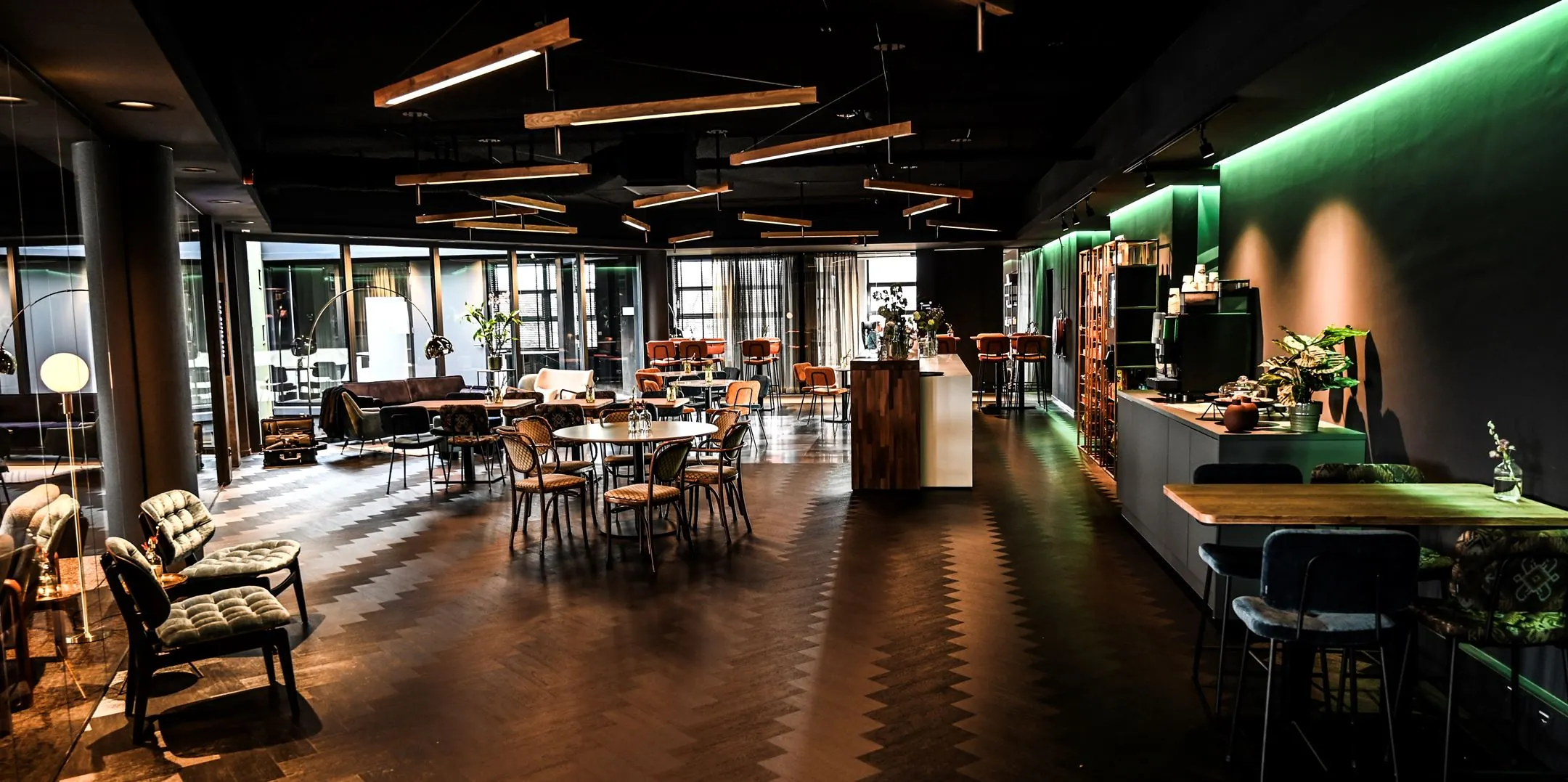 Moderne en sfeervol ingerichte lounge- en werkruimte aan de Lange Amerikaweg 61, met zithoeken, eettafels en een open keuken.