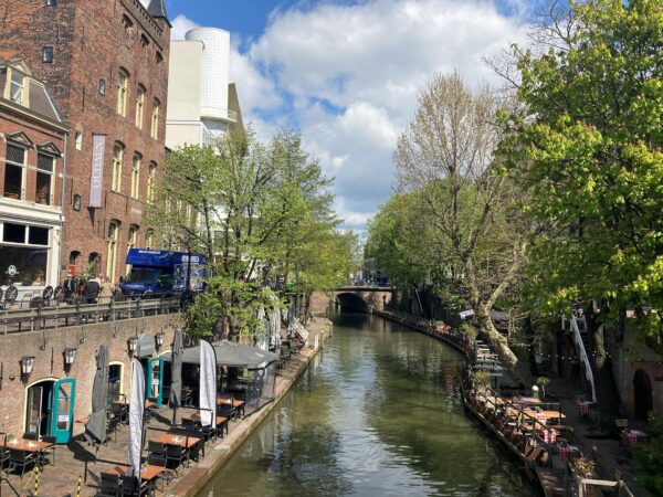 Gezellige gracht in de Lange Viestraat in Utrecht met terrasjes langs het water en historische gebouwen.