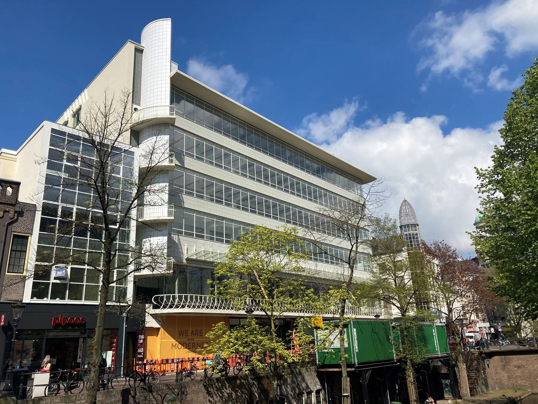 Modernistisch wit gebouw aan de Lange Viestraat 2 in Utrecht met veel glasgevels en een opvallend afgerond hoekelement.
