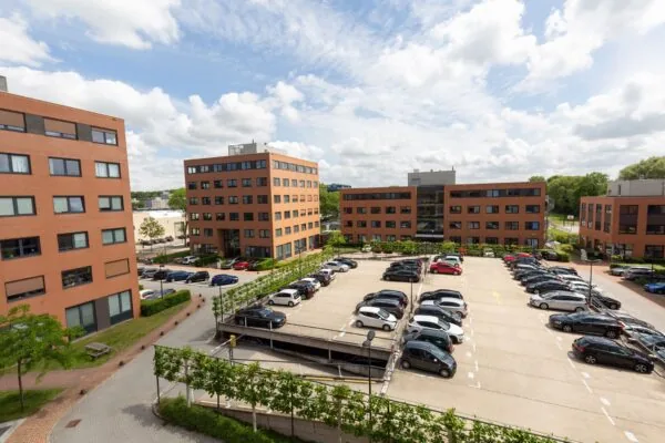 Parkeerplaats aan de Langekleiweg omringd door moderne kantoorgebouwen met rode bakstenen.