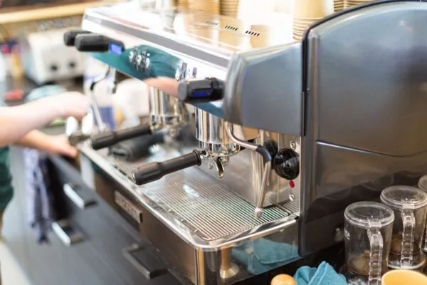 Professionele espressomachine in gebruik op locatie Langekleiweg 7, met koffieaccessoires op het aanrecht.