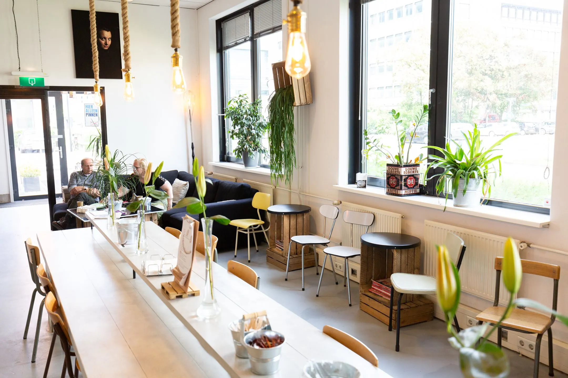 Gezellige zithoek in een lichte, modern ingerichte ruimte aan de Langekleiweg 8 met planten, vintage meubilair en grote ramen.