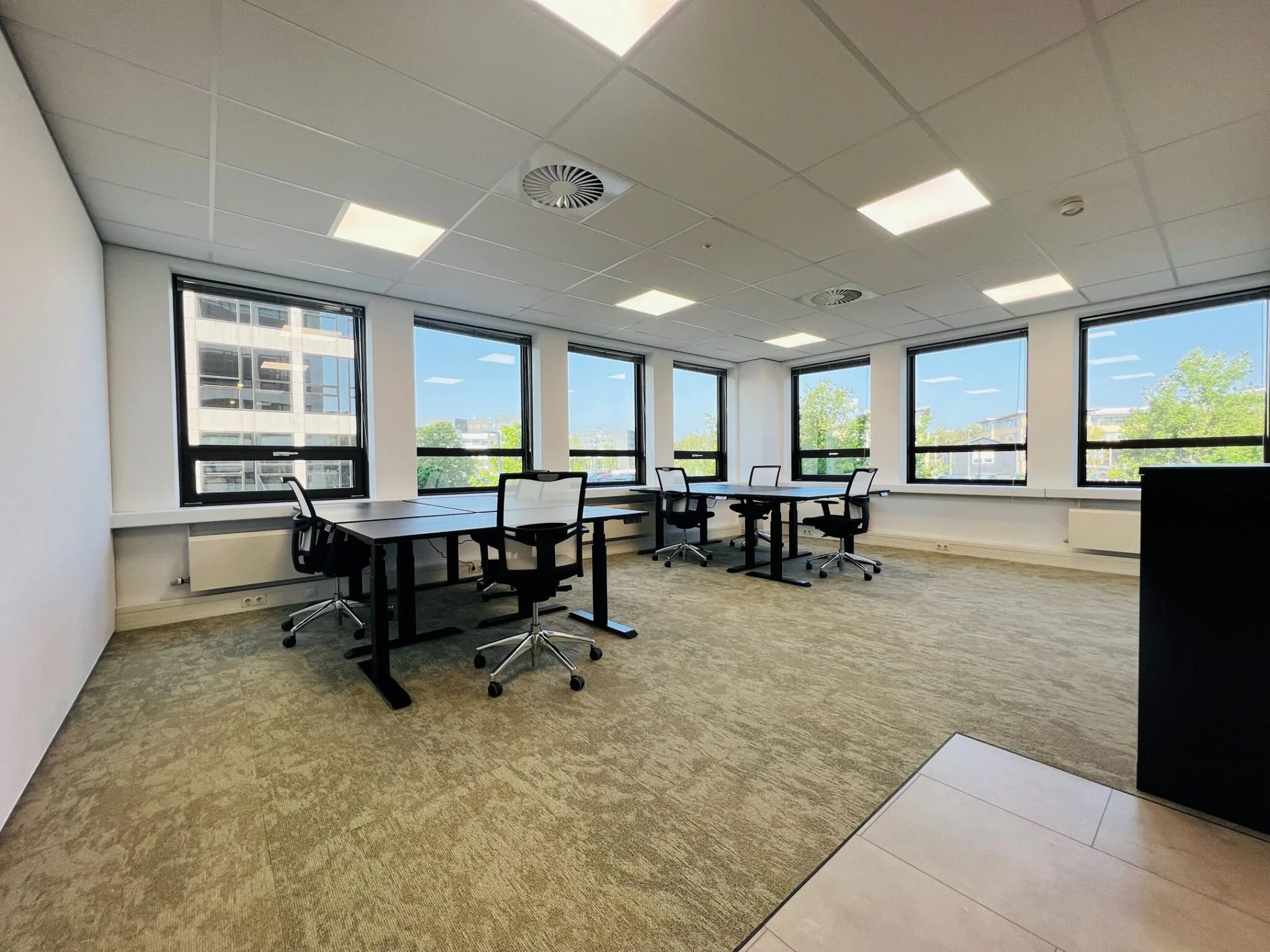 Moderne, lichte kantoorruimte met meerdere bureaus en bureaustoelen bij grote ramen in gebouw Marathon 2.