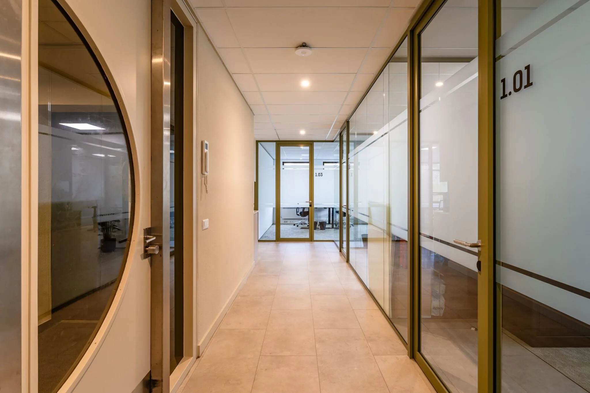 Gang in kantoorpand Marathon 2 met glazen kantoordeuren en zicht op vergaderruimte 1.03.
