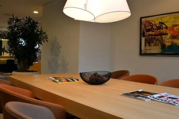 Vergaderruimte aan de Marshalllaan met houten tafel, moderne stoelen, tijdschriften en een kunstwerk aan de muur.