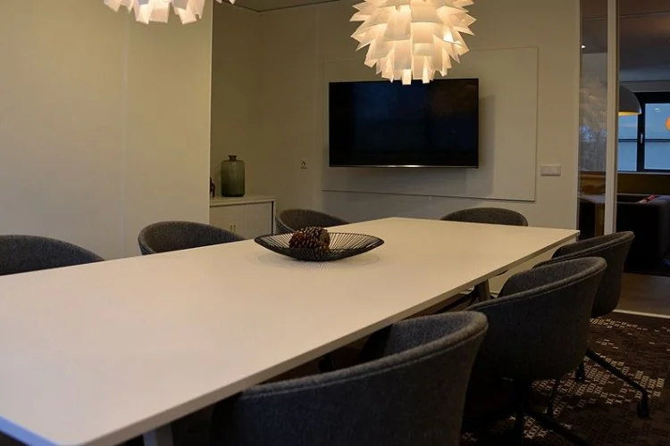 Vergaderruimte aan de Marshalllaan met een lange witte tafel, moderne stoelen en opvallende hanglampen.