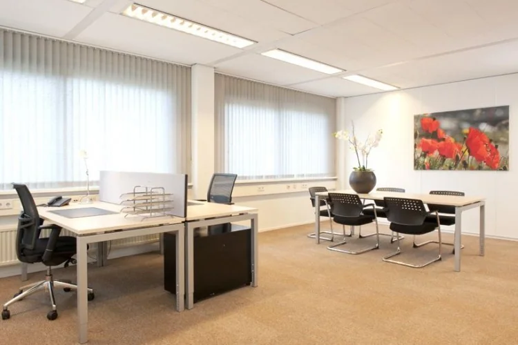 Modern ingericht kantoor aan de Marshalllaan 2 met werkplekken, vergadertafel en grote ramen met verticale jaloezieën.