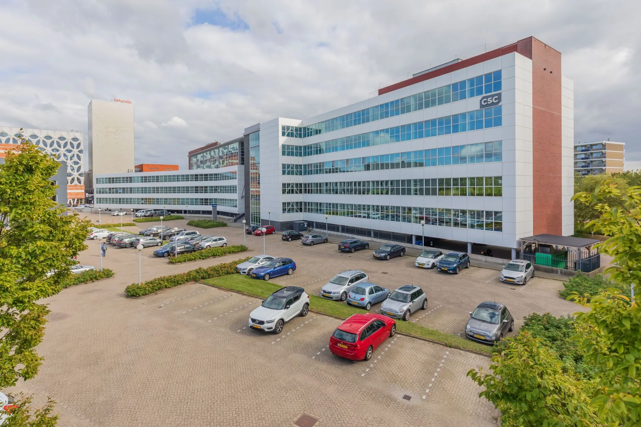 Kantoorgebouw aan de Mendelweg 32 met grote parkeerplaats op de voorgrond.