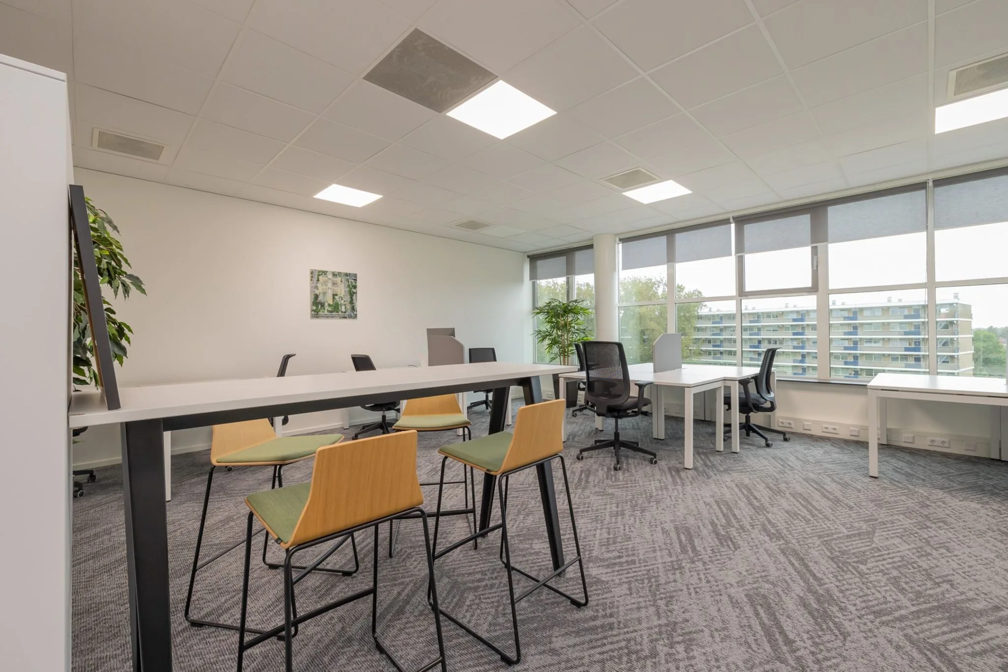 Moderne en lichte kantoorruimte in Mendelweg 32 met werkplekken, hoge tafels en kantoorstoelen.