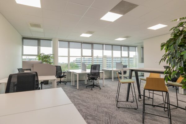 Modern en licht kantoorinterieur aan de Mendelweg 32 met werkplekken, bureaustoelen en hoge tafels met krukken.