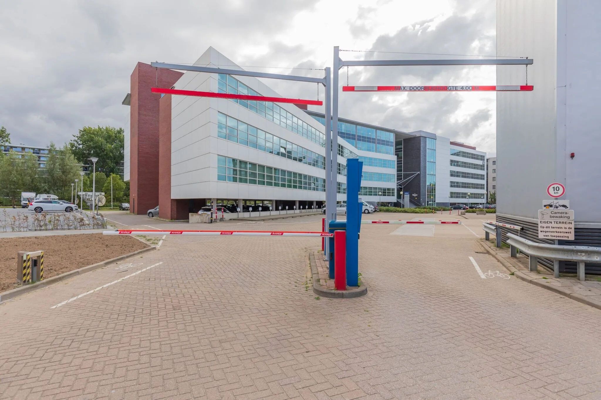 Toegangsweg met slagbomen en hoogtebegrenzer bij kantoorgebouw aan de Mendelweg 32.