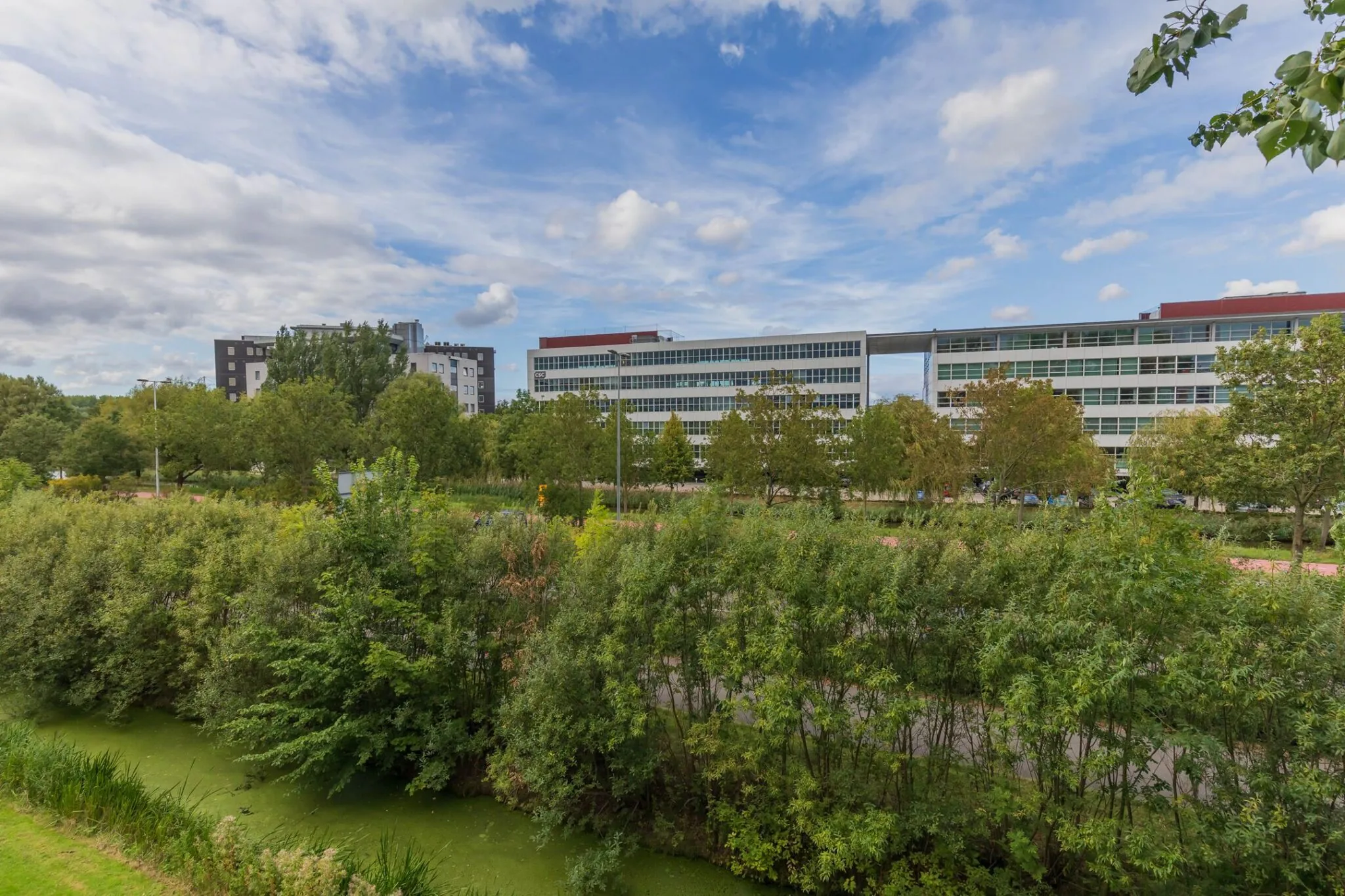 Kantoorgebouw aan de Mendelweg 32 in Leiden, omgeven door groen en een waterpartij.