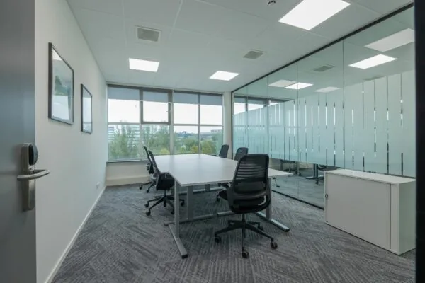 Vergaderruimte met zes bureaustoelen, een grote tafel en een glazen wand in het kantoor aan de Mendelweg 32.