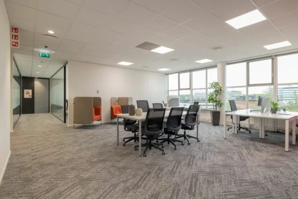 Moderne en lichte kantoorruimte aan de Mendelweg 32 met werkplekken, vergadertafel en zicht op omliggende kantoorpanden.