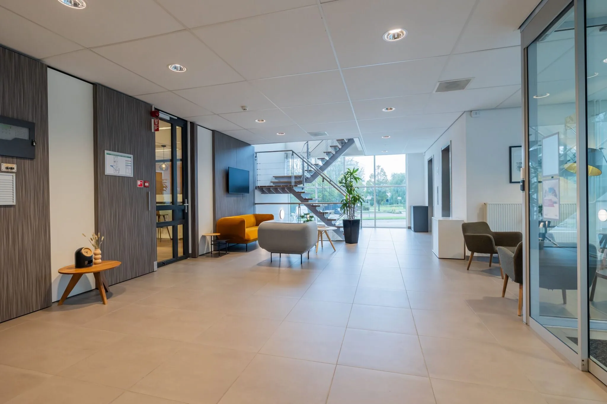 Moderne entreehal van het kantoorgebouw aan de Mendelweg 32 met zithoek, glazen wand en trap naar boven.