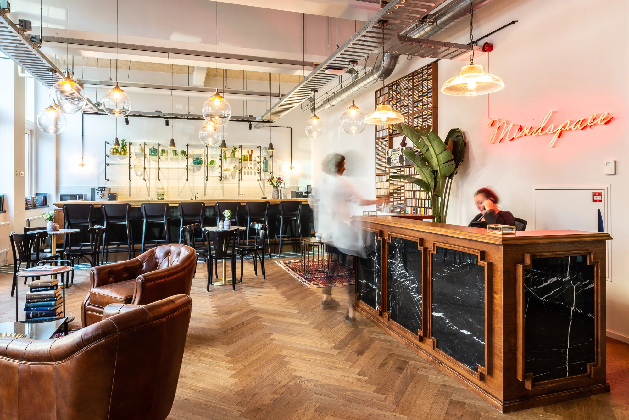 Stijlvolle ontvangst- en loungehoek van Mindspace Utrecht met een marmeren balie, leren fauteuils en een moderne bar.